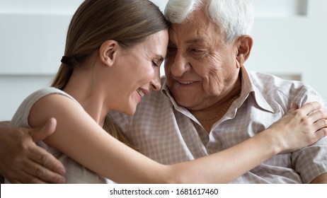 Loving Adult Daughter And Older Father Touching Foreheads Close Up, Family Enjoying Tender Moment, Smiling Young Woman And Mature Dad Or Grandfather Hugging, Two Generations Expressing Love