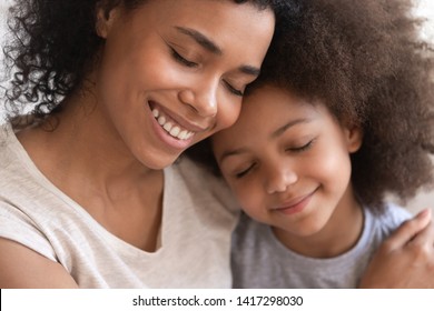 Loving affectionate family young african american mother holding embracing cute little kid daughter, happy black mom foster parent hug small mixed race child cuddling and bonding with eyes closed - Shutterstock ID 1417298030