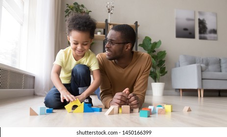 Loving African American Dad Lying On Floor Have Fun Play With Little Son Use Colorful Blocks, Happy Black Father And Preschooler Boy Child Learn Together Engaged In Funny Game With Building Bricks