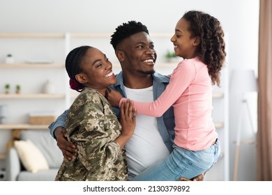 Loving African American Family Celebrating Reunion With Mom Soldier, Happy Black Man Father Carrying Child Daughter, Hugging Mother In Military Uniform And Smiling, Home Interior, Copy Space