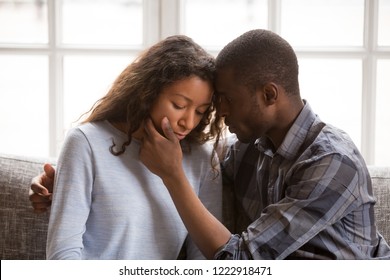 Loving African American husband touching wife face with tender, apologizing after quarrel, man comforting woman, health problem, interruption unwanted pregnancy, miscarriage, relationships trouble
