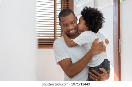 Loving African American Little Boy Kissing His Father At Home. Happy Of Black Family. African Dad And Son In White T-Shirt Hugging.