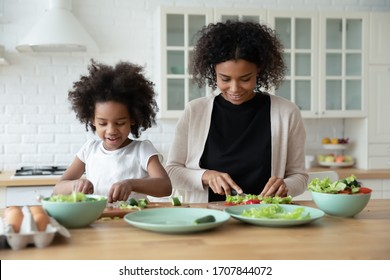 Loving African American Mother And Cute Little Preschooler Daughter Have Fun Cooking In Modern Kitchen Together, Happy Biracial Mom And Small Girl Child Prepare Salad, Healthy Lifestyle, Diet Concept