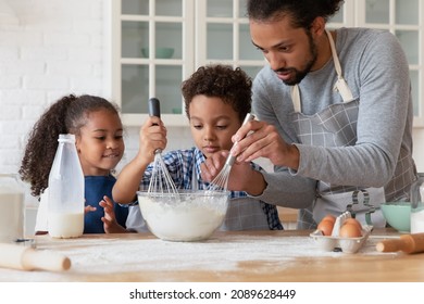 Loving African dad teach kids to cook in kitchen, hold beaters mixing ingredients in bowl preparing dough for cookies, parent share family recipe to preschool son and daughter. Hobby, cookery concept - Powered by Shutterstock