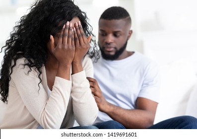 Loving african man soothing crying woman, apologizing after quarrel, boyfriend hugging girlfriend shoulder, empty space