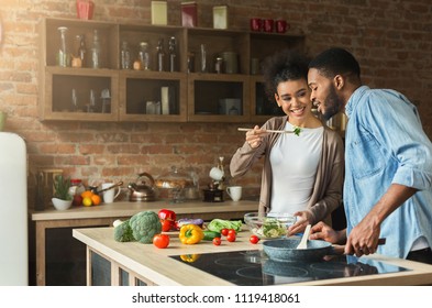 Loving african-american couple preparing vegetable salad for dinner in loft kitchen - Powered by Shutterstock