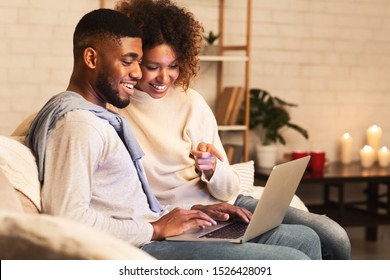 Loving Afro Couple Choosing Film On Laptop, Resting Together At Cozy Winter Evening, Free Space