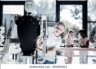 Loving All These Innovative Technologies. Charming Young Gentleman Looking Into The Camera And Grinning Broadly While Posing With A Human Like Robot.