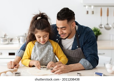 Loving Arab Dad And Little Daughter Having Fun Together While Baking In Kitchen, Cute Small Girl Cutting Out Different Cookie Shapes From Dough, Enjoying Cooking At Home With Daddy, Free Space