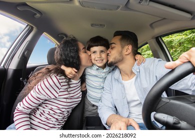 Loving Arabic Parents Kissing Their Little Son While Sitting In Car Together, Happy Middle Eastern Family Of Three Enjoying Summer Road Trip In New Automobile, Closeup Shot Inside Of Vehicle