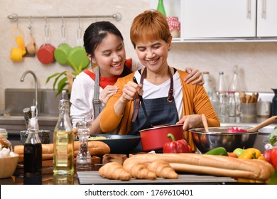 Loving Asian family of mother and daughter cooking in kitchen making healthy food together feeling fun