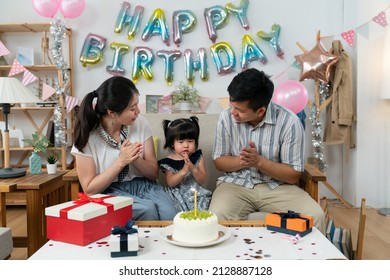 Loving Asian Father And Mother Looking At Their Cute Baby Girl As They Are Singing Happy Birthday Song And Celebrating Her Two Year Old Birthday At Home