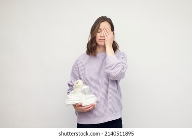 Loving Beautiful Mother With Diapers, Teddy And A Baby Bottle In One Hand Makes Tired Expression. Concept: Mom Is Tired And Motherhood. White Background. Space For Text. Mom Chores.