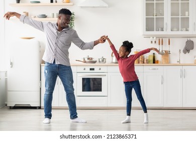 Loving black father and cute daughter dancing at kitchen, handsome young dad teaching his little girl dancing waltz while spending time together at home, copy space, full length