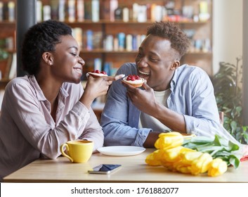 Loving black guy and girl eating yummy sweet tartlets at coffee shop - Powered by Shutterstock