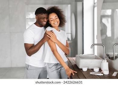 Loving Black Husband Hugging His Happy Beautiful Wife Standing In Modern Bathroom Together, Enjoying Romance Of Daily Beauty Routine In The Morning. Family Pampering And Self Care - Powered by Shutterstock