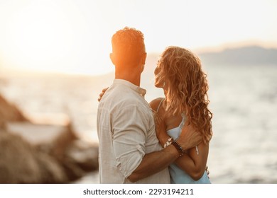 A loving cheerful couple are enjoying a summer vacation and hugging on the sea beach at sunset. - Powered by Shutterstock