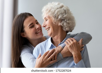 Loving Cheerful Grown Up Daughter Hugs Elderly Mother From Behind, Multi Generational Relatives Beautiful Women Enjoy Time Together Laughing Having Fun, Love Care Understanding Concept, Close Up Image