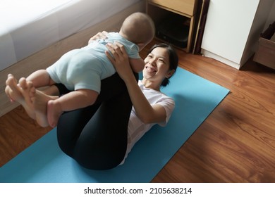 Loving Chinese Mom Exercising Playing With Her Baby At Home, Happy Asian Young Mother Lying On The Floor Lifting Little Boy In The Air, Yoga, Workout