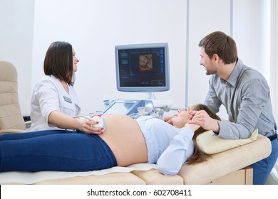 Loving couple attending doctor for pregnancy ultrasound procedure