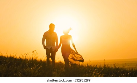 loving couple - brave young man and beautiful girl at sunset silhouette