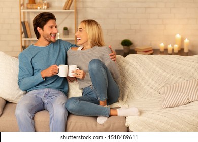 Loving Couple Clanging Cups Together Sitting On Couch Having Night Date At Home. Copy Space, Selective Focus