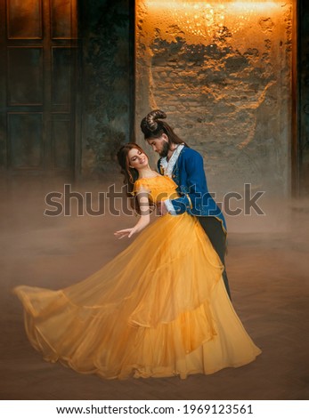 loving couple is dancing at fairy ball. Happy beauty woman fantasy princess in yellow dress and guy is enchanted guy, horns on head Girl whirls in arms of male prince. Man monster carnival costume
