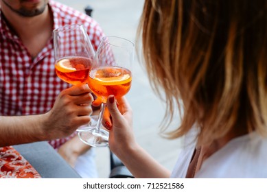 A loving couple drinks apelol spritz in Italy, hands with glasses close-up