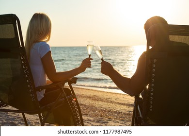 A loving couple drinks champagne on the beach. Romantic.