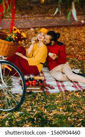 Loving Couple Eating Cheesy Snacks Sitting On A Mat In The Park. Autumn Picnic