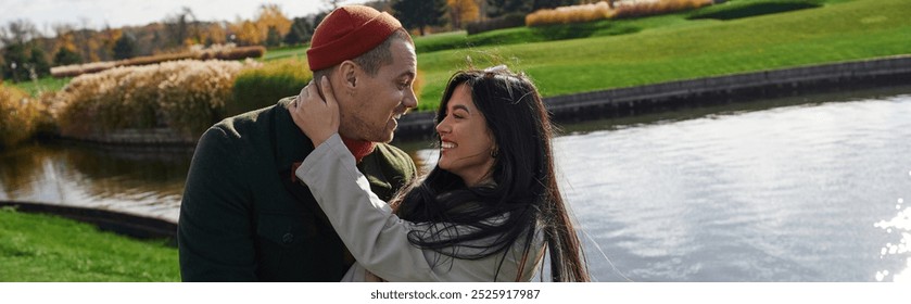 A loving couple embraces affectionately against a backdrop of vibrant autumn colors by the lake. - Powered by Shutterstock