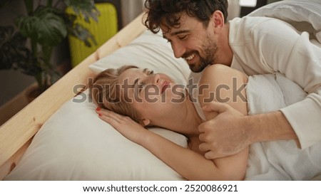 A loving couple enjoys an intimate moment together, lying in a cozy bedroom setting, reflecting affection and comfort.