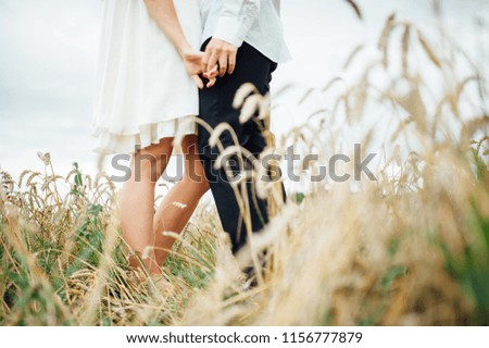 
Loving couple in a field with colic, stylish hairstyles, and white clothes