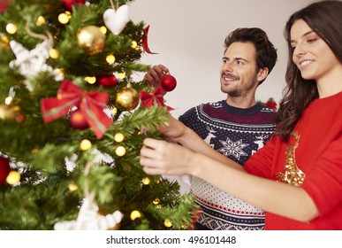 Loving Couple Hanging Decorations On Christmas Tree