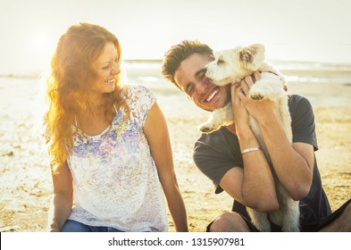 Loving Couple Having Fun With Their Dog At The Beach On Vacation. Concept About People, Animals And Lifestyle