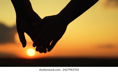 Loving couple holding hands against backdrop of sun. Close up of guy, girl meet holding hands together. Hands of man, woman touch hands outdoors. Happy family, husband, wife. Family in park at sunset - Powered by Shutterstock