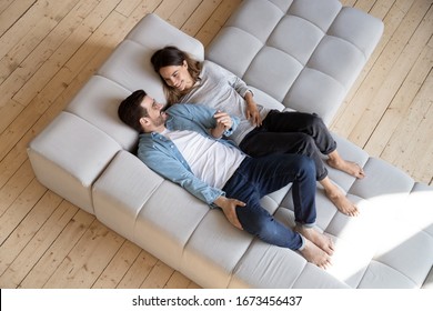 Loving Couple Holding Hands, Relaxing On Cozy Sofa In Modern Living Room Top View, Happy Beautiful Woman And Man Resting On Comfortable Couch Together, Spending Lazy Weekend, Enjoying Leisure Time