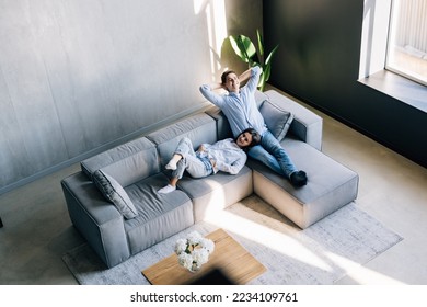 Loving couple holding hands, relaxing on cozy sofa in modern living room top view, happy beautiful woman and man resting on comfortable couch together, spending lazy weekend, enjoying leisure time - Powered by Shutterstock