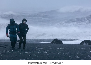 A Loving Couple Holding Hands Walks Along The Shore Of The Raging Ocean. Long Exposure. Valentine's Day. In Distress And Lust