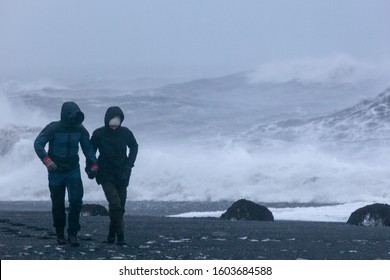 A Loving Couple Holding Hands Walks Along The Shore Of The Raging Ocean. Long Exposure. Valentine's Day. In Distress And Lust