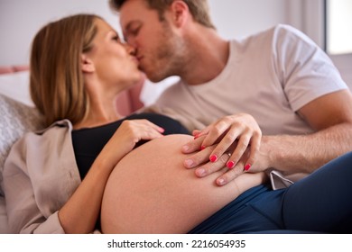 Loving Couple At Home Lying On Bed With Man Touching Pregnant Woman's Stomach - Powered by Shutterstock