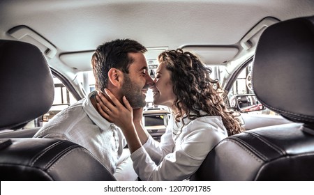 loving couple kissing in the new car in car showroom