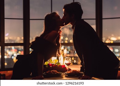 Loving couple kissing on panoramic window background overlooking nigth city. Romantic place for romantic evening concept - Powered by Shutterstock