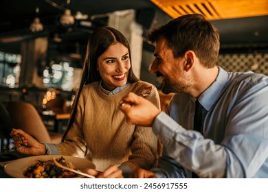 A loving couple laughing while eating in the restaurant afterwork - Powered by Shutterstock