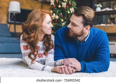 loving couple laying on floor and holding hands on christmas