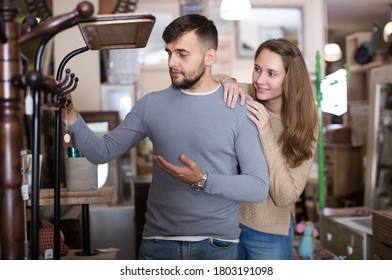 Loving Couple Looking For Hallstand In Shop Of Secondhand Furniture