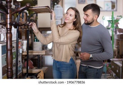 Loving Couple Looking For Hallstand In Shop Of Secondhand Furniture