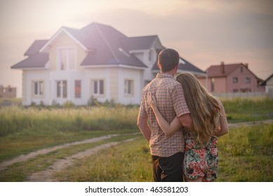 Loving Couple Looking At Their Home In Sunset. Copy Space