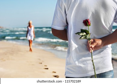 Loving Couple - Man With Rose Waiting His Woman On The Sea Beach At Summer - The Romantic Date Or Wedding Or Valentines Day Concept