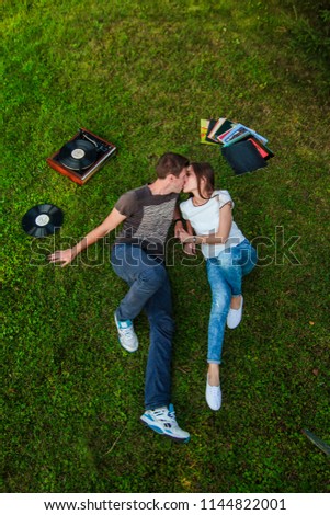 Loving couple on the grass lying. next to vinyl records on a sunny summer day